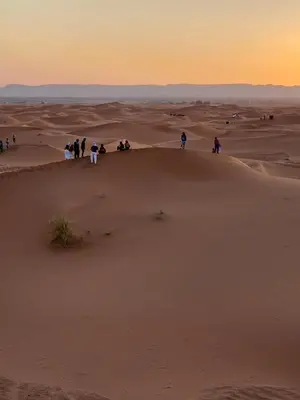 people standing on top of a sand dune in the desert at Desert Live Luxury Camp in Merzouga