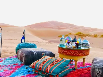 a table in the middle of a desert with drinks at Desert Live Luxury Camp in Merzouga