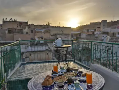a table with food on a balcony with a view of a city at Dar El Kendil in Fès