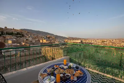 a table on a balcony with a view of a city at Dar El Kendil in Fès