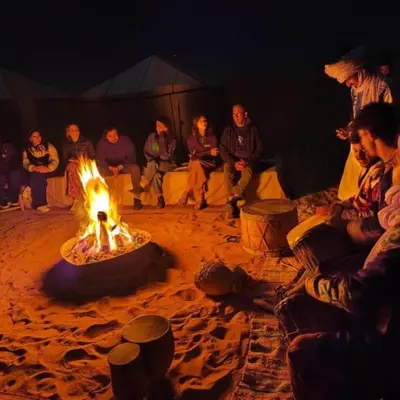 a group of people sitting around a fire in a tent at Oasis Desert Luxury Camp in Merzouga