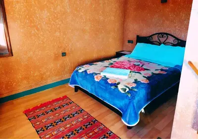 a bedroom with a bed with a blue comforter and a rug at SUD-EST palace in Ait Gmat