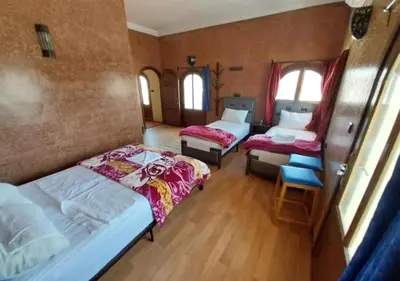 a room with three beds and a chair in it at SUD-EST palace in Ait Gmat