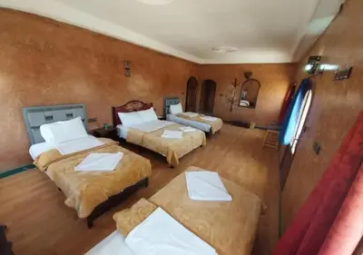 a room with two beds and two tables in it at SUD-EST palace in Ait Gmat