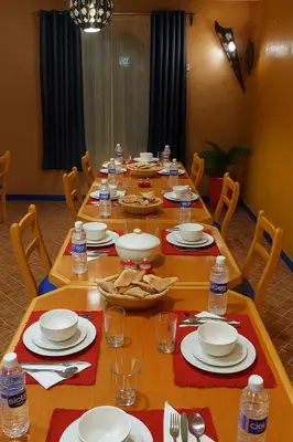 a long table with chairs and plates and bottles of water at SUD-EST palace in Ait Gmat