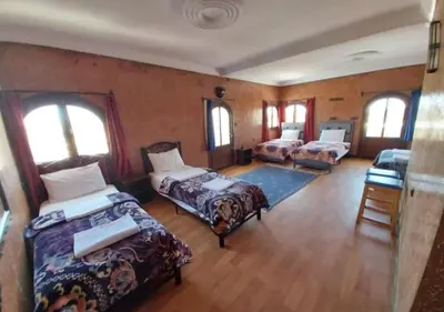 a room with three beds in a room with windows at SUD-EST palace in Ait Gmat