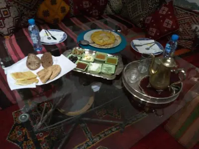 a glass table with a plate of food on it at Maison d'hotes Ait Bou Izryane in Timoulilt