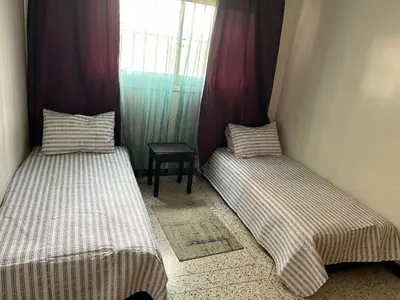 two beds in a small room with a window at Appartement tout confort in Fès