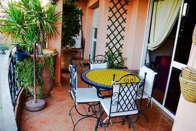 a table and chairs on a patio with plants at appartement el harti in Oulad Akkou