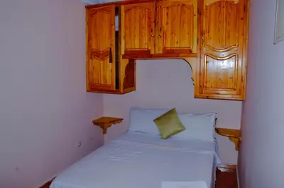 a small bedroom with a bed and wooden cabinets at appartement el harti in Oulad Akkou