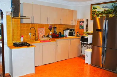 a kitchen with white cabinets and a stainless steel refrigerator at appartement el harti in Oulad Akkou