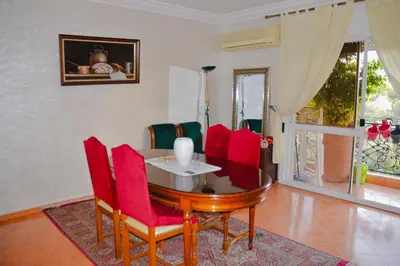 a dining room with a table and red chairs at appartement el harti in Oulad Akkou