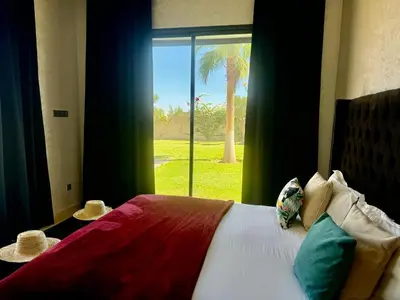 a bedroom with a bed and a window with a palm tree at Villa de luxe à louer à la journée A Marrakech in Marrakech