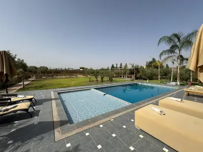 a swimming pool in a resort with chairs and trees at Luxury family villa with private pool in Douar bel Rhanodour