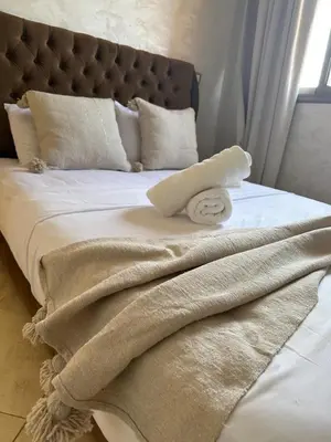 a bed with white blankets and pillows on it at Luxury family villa with private pool in Douar bel Rhanodour
