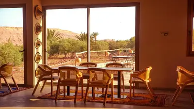 a dining room with a table and chairs and a large window at Dar Bikouch in Aït Ben Haddou