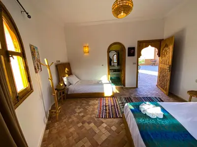 a bedroom with two beds and a hallway with a doorway at Dar Bikouch in Aït Ben Haddou