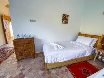a bedroom with a bed and a wooden night stand at Dar Bikouch in Aït Ben Haddou