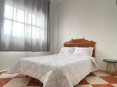 a bedroom with a bed with a wooden headboard and a window at Résidence Kawtar in Meknès
