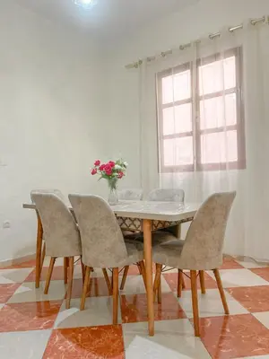 a dining room table with chairs and a vase of flowers at Résidence Kawtar in Meknès