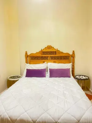 a bedroom with a large bed with purple and white pillows at Résidence Kawtar in Meknès