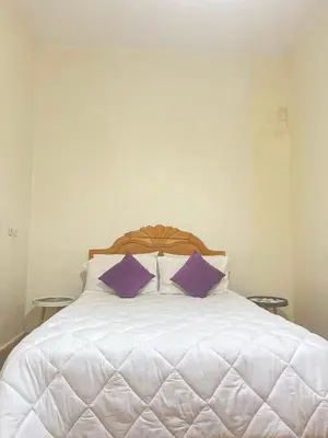 a white bed with two purple pillows on it at Résidence Kawtar in Meknès