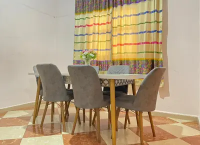 a dining room table with four chairs and a colorful curtain at Résidence Kawtar in Meknès