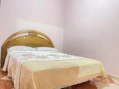 a bed with a wooden headboard in a room at Résidence Kawtar in Meknès