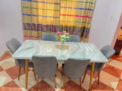 a table with chairs and a vase of flowers on it at Résidence Kawtar in Meknès