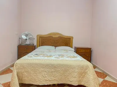 a bedroom with a bed and two dressers and a fan at Résidence Kawtar in Meknès