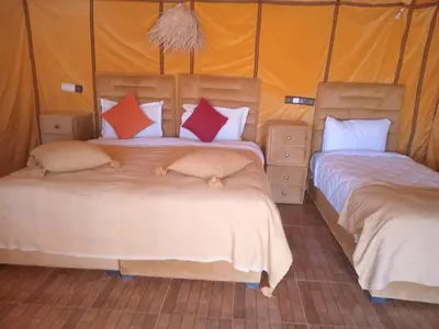 two beds in a room with orange walls at Good vibes desert camp in Merzouga