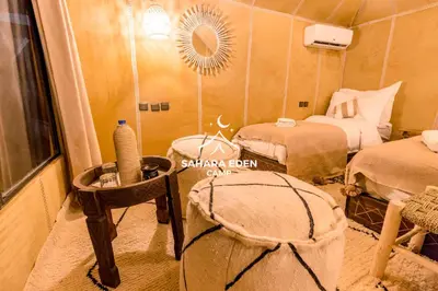 a room with two beds and a table with a mirror at Sahara Eden Camp in Merzouga