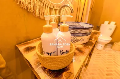 two bottles of soap on a wooden table in a bathroom at Sahara Eden Camp in Merzouga