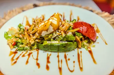 a plate of food with a salad and sauce at Sahara Eden Camp in Merzouga