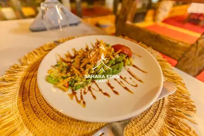 a plate of food with a salad on a table at Sahara Eden Camp in Merzouga