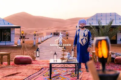 a man standing in front of a table in the desert at Sahara Eden Camp in Merzouga