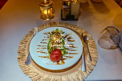 a plate of food on a table with silverware at Sahara Eden Camp in Merzouga