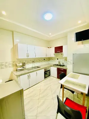 a kitchen with white cabinets and a table and chairs at New dream home in Fès