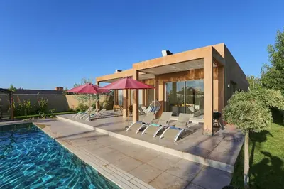 a house with a swimming pool with chairs and umbrellas at Villa shams Marrakech , Private Pool and Hammam in Azib Oulad Lâdem