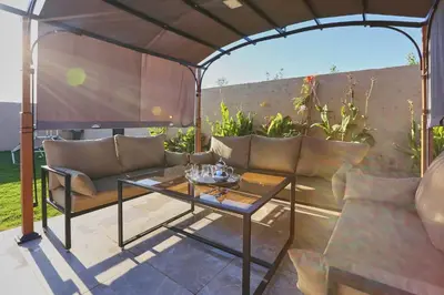 a patio with a table and couches under an arbor at Villa shams Marrakech , Private Pool and Hammam in Azib Oulad Lâdem