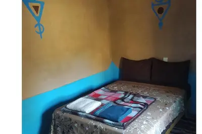 a bed with a blanket on it in a room at Desert house in Merzouga