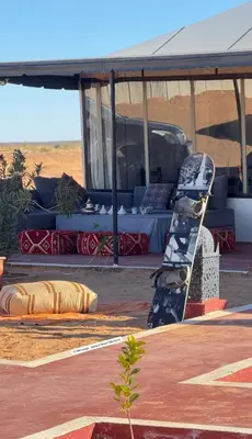 a tent with chairs and a couch in the desert at Desert Pearl Camp Merzouga in Merzouga