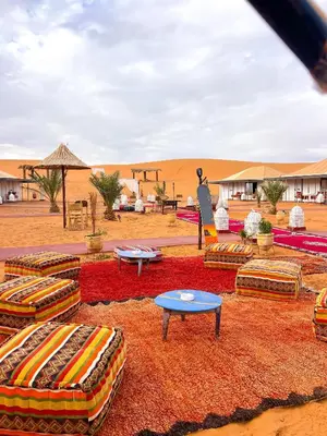 a desert encampment with couches and tables in the desert at Desert Pearl Camp Merzouga in Merzouga