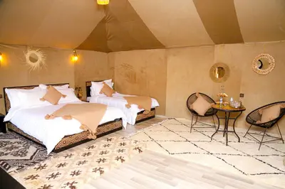 a bedroom with two beds and a table and chairs at Desert Pearl Camp Merzouga in Merzouga