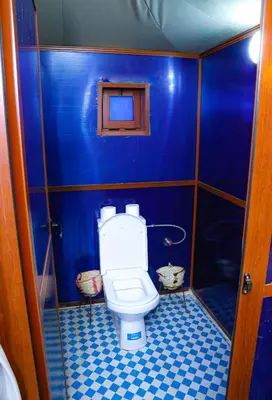 a bathroom with a toilet in a blue stall at Desert Pearl Camp Merzouga in Merzouga