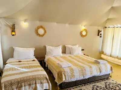 a bedroom with two beds and two mirrors on the wall at Nights luxury camp in Merzouga