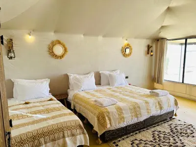 a bedroom with two beds and a mirror on the wall at Nights luxury camp in Merzouga