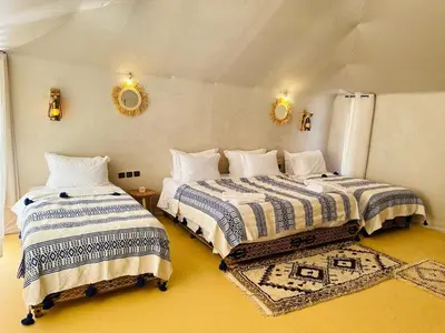 two beds in a room with yellow floors at Nights luxury camp in Merzouga