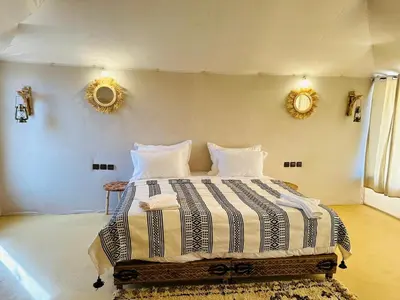 a bedroom with a large bed with two mirrors on the wall at Nights luxury camp in Merzouga