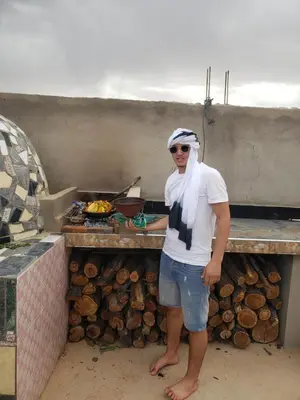a man standing in front of a food stand at Agoudim Nikhartan in Tinerhir